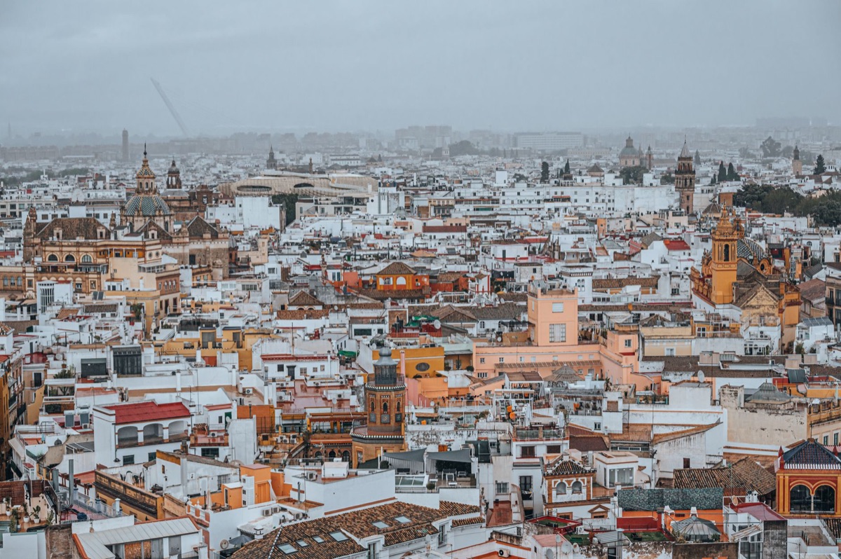 Pessoa com capa e máscara, em um ambiente urbano, representando a população secular e a diversidade religiosa em Espanha.